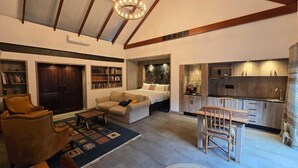 Ein modernes Wohnzimmer mit Sofa, Sessel und Couchtisch, ein Schlafzimmer mit Bett und Nachttisch sowie eine Küche mit Essbereich.