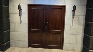 Eine Reihe von zweifl ügeligen Holztüren mit modernem Design, eingerahmt von Steinwänden und zwei Wandleuchten.