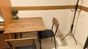 A small wooden table with a black chair, a potted plant, and a coat rack against a wall with a wooden accent. - 30sec walk to Tsutenkaku/1 stop to Namba Sta./AH66 (Ebisu Higashi Naniwa-Ward,Osaka City)