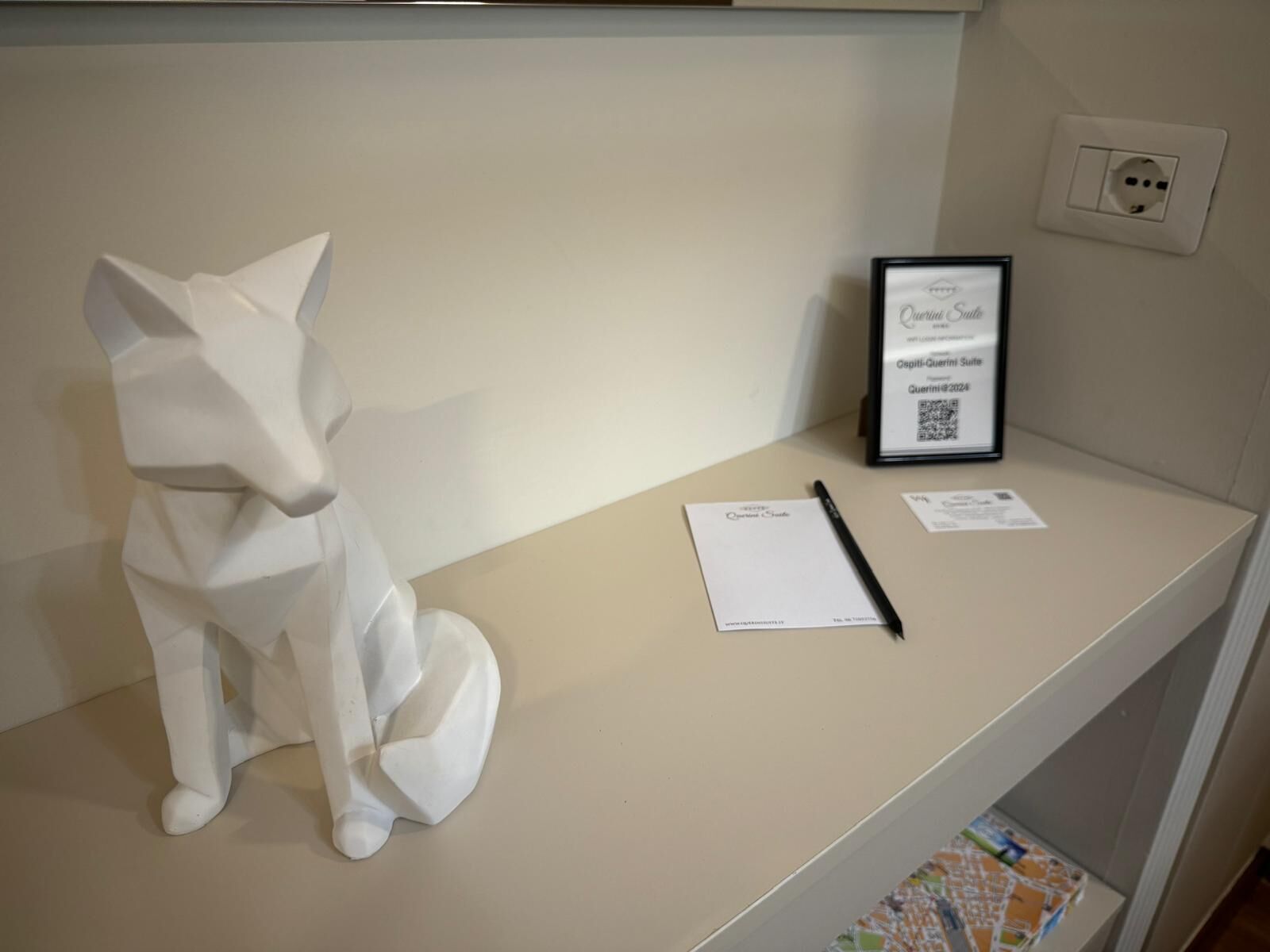 A white cat sculpture on a desk with a framed certificate, a pen, and papers.