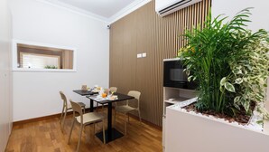 A dining area with a table set for two, a small window, and a large potted plant. - Querini Suite (Rome)