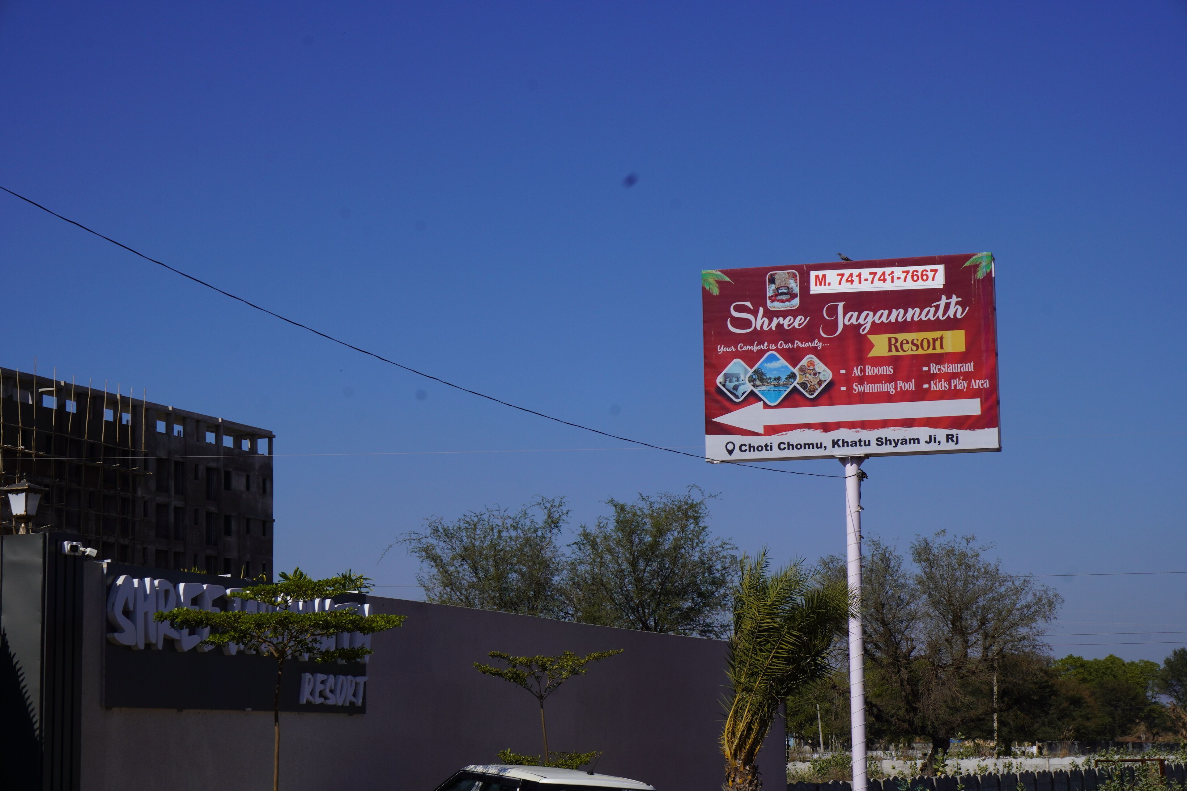 A signboard for Shree Jagannath Resort advertising amenities like AC rooms, a restaurant, swimming pool, and kids play area.
