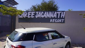 A white SUV parked in front of a sign for Shree Jagannath Resort. - Shree Jagannath Resort (Shri Madhopur)