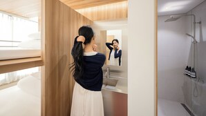 A modern bathroom with a wooden ceiling, a glass shower enclosure, and a mirror reflecting the room. - Loft13 Hostel (Seoul)