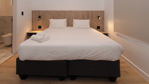 Ein modernes Schlafzimmer mit einem großen Bett, einem Holz-Kopfteil und Nachttischlampen.