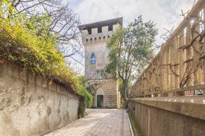 Un carreró estret amb una paret de pedra a un costat i un edifici amb una torre a l'altre.