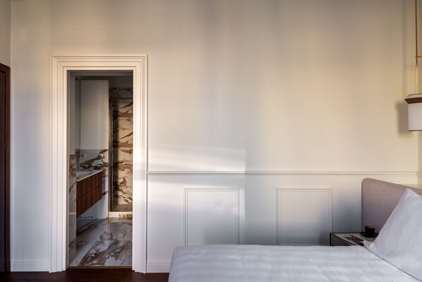 A bedroom with a bed, a nightstand, and a bathroom visible through an open door. - Cavalieri Palace Roma (Rome)