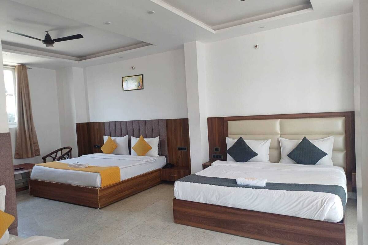 Una habitación de hotel con dos camas, un ventilador de techo y un cuadro en la pared.
