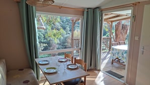 Un comedor con una mesa preparada para cuatro, ventanas amplias y vistas al exterior.