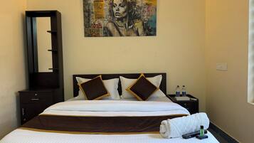 A hotel room with a large bed, a nightstand, a mirror, and a painting on the wall.