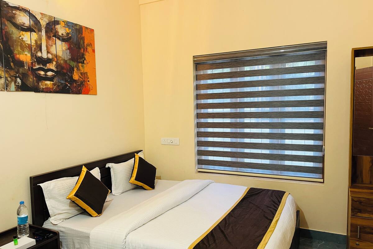 Een hotelkamer met een bed, een nachtkastje, een waterfles en een schilderij aan de muur.