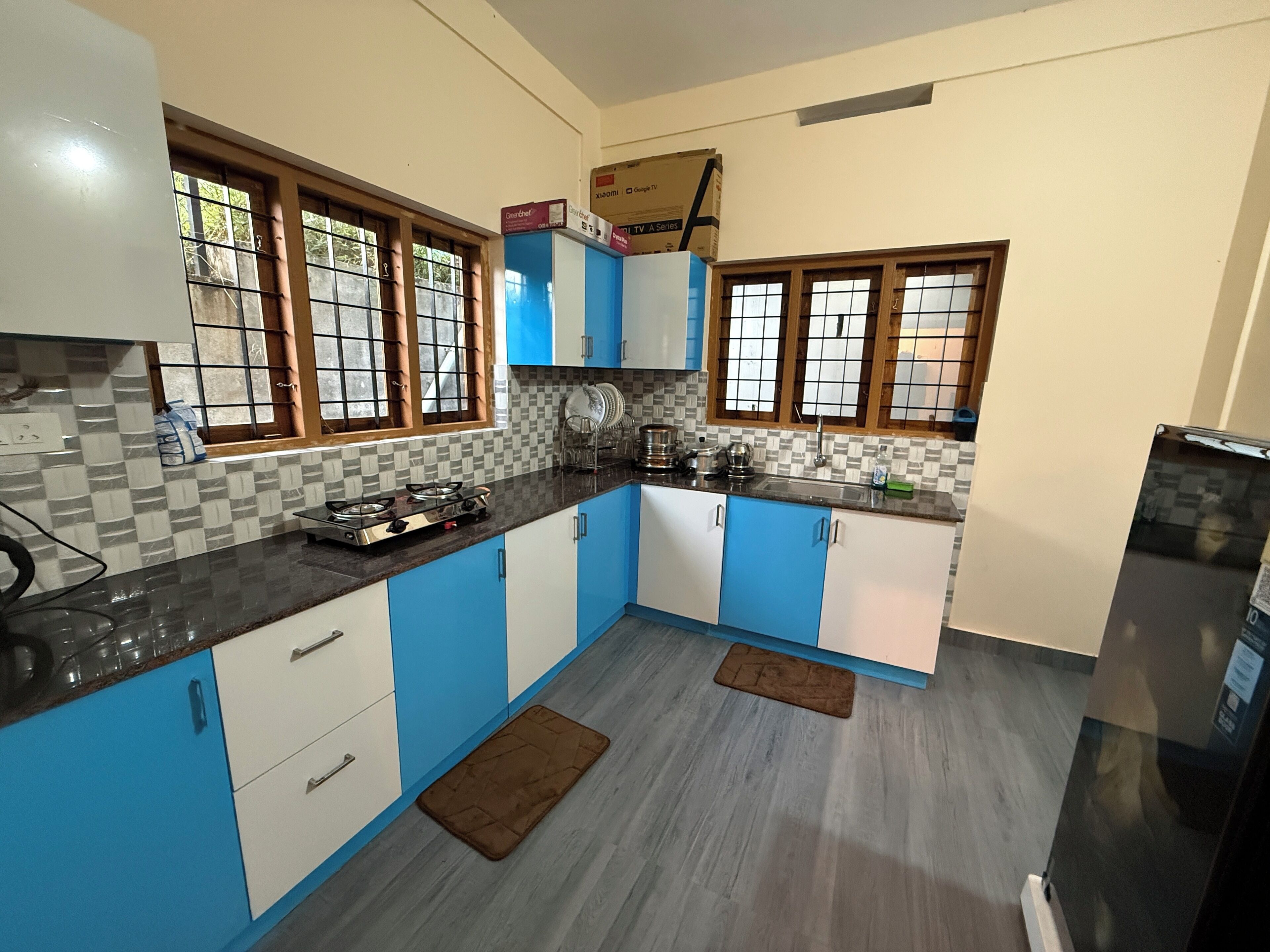 A kitchen with blue and white cabinets, a gas stove, and a refrigerator.
