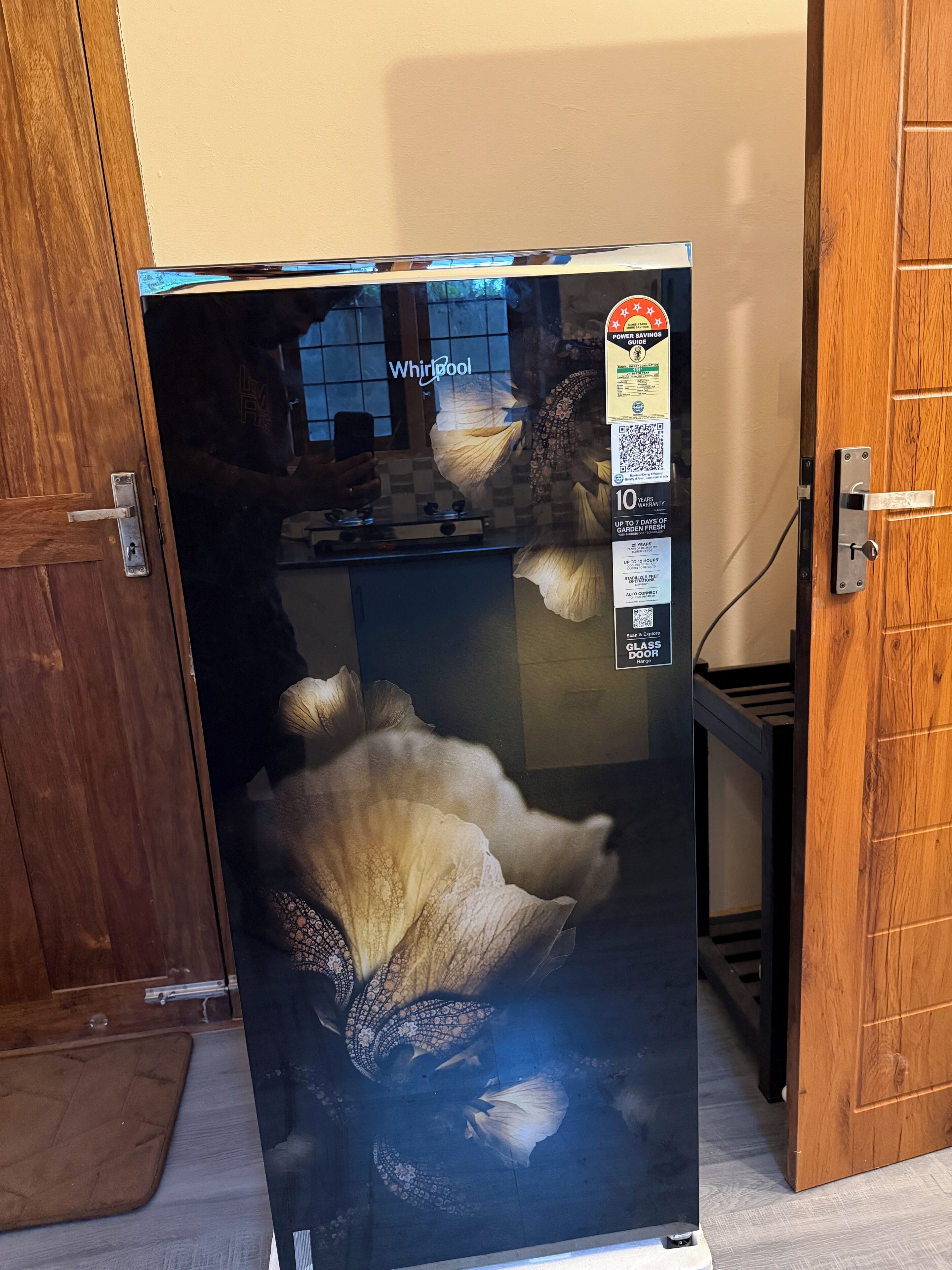 A refrigerator with a Whirlpool logo, a power savings guide sticker, and a QR code.