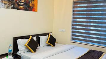 A hotel room with a bed, a nightstand, a water bottle, and a painting on the wall.