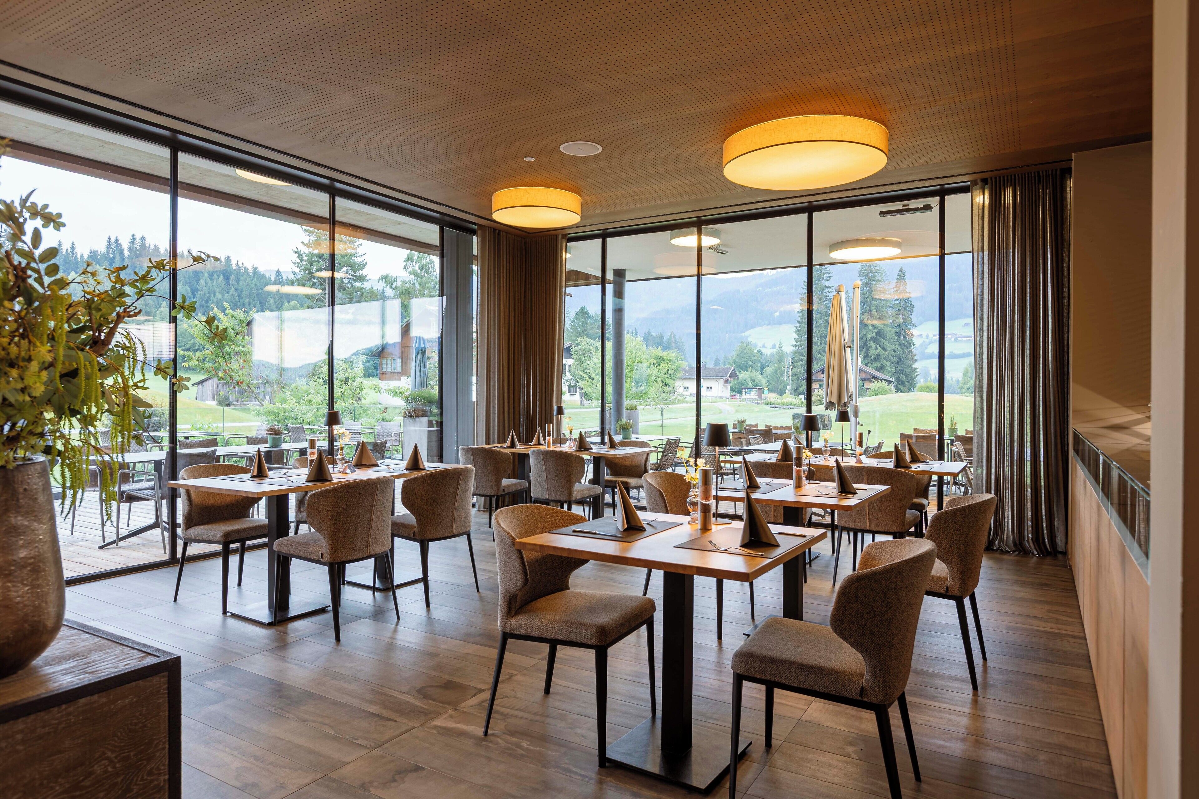 Un restaurante con vistas a las montañas, mesas y sillas de madera.