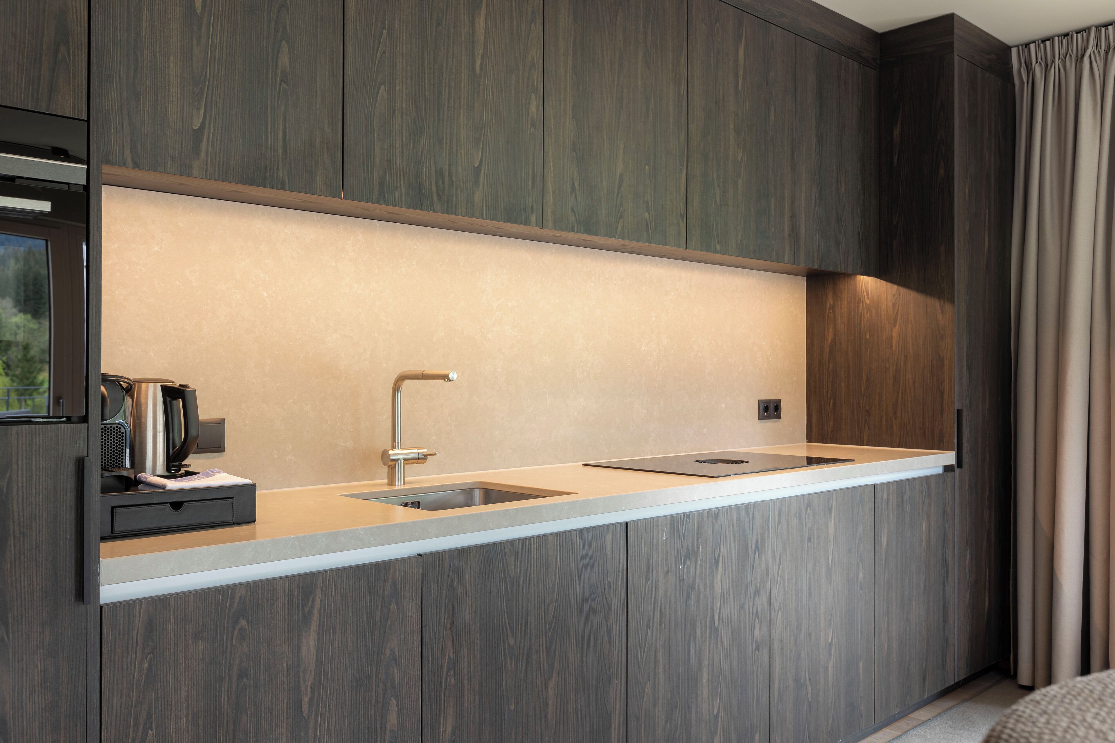 A modern kitchen with wooden cabinetry, a stainless steel sink, and a built-in coffee maker.