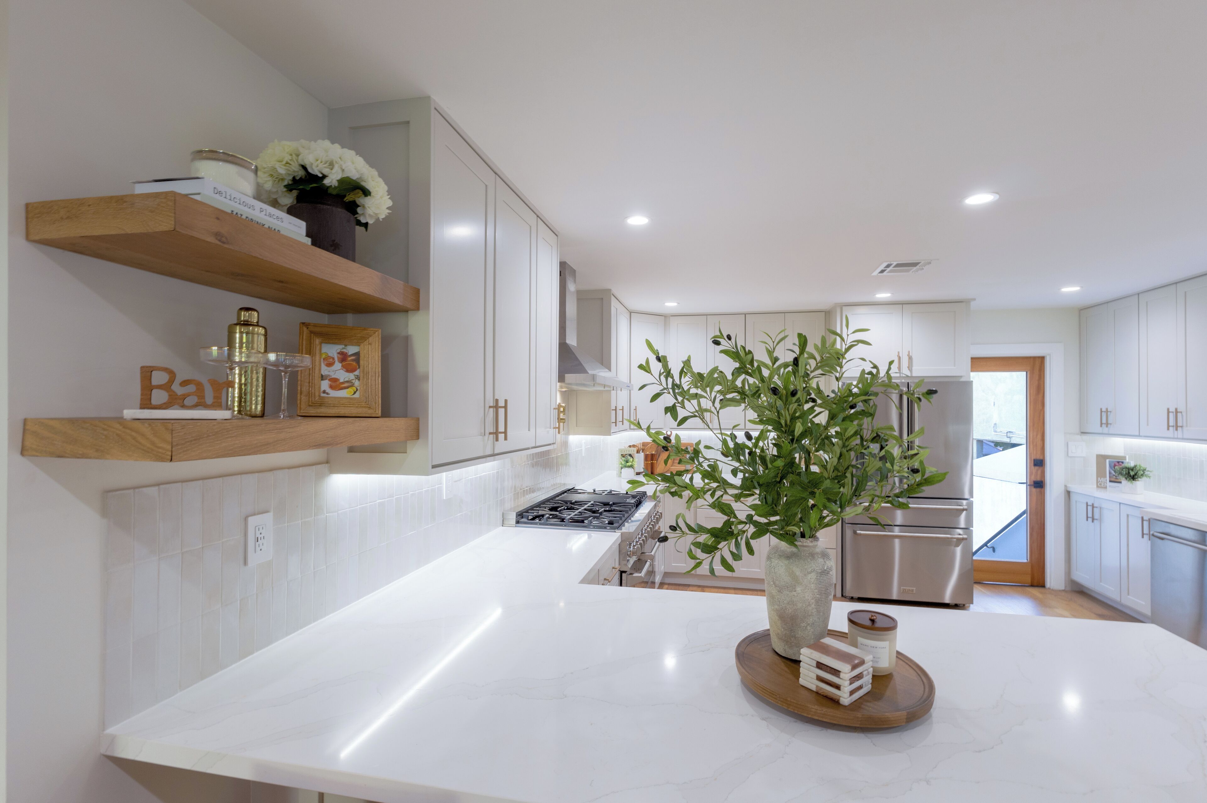 A modern kitchen with white cabinetry, a central island, and a stainless steel refrigerator.
