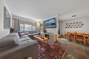 A modern living room with a gray sectional sofa, a wooden coffee table, and a fireplace. - Nestle Inn Hideaway - Toby Creek Lodge Unit 213 (Area F (Columbia Lake/Windermere Lake))