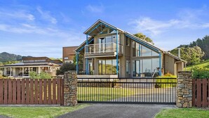 Een modern, twee verdiepingen tellend huis met een balkon, een stenen poort en vrij uitzicht op het omliggende landschap.