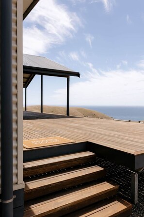 Une terrasse en bois offrant une vue sur la plage et l’océan.