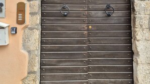 Eine große, bogenförmige Holztür mit zwei Metallringen, einem Schild für ein Gästehaus und der Zahl '12' darüber.
