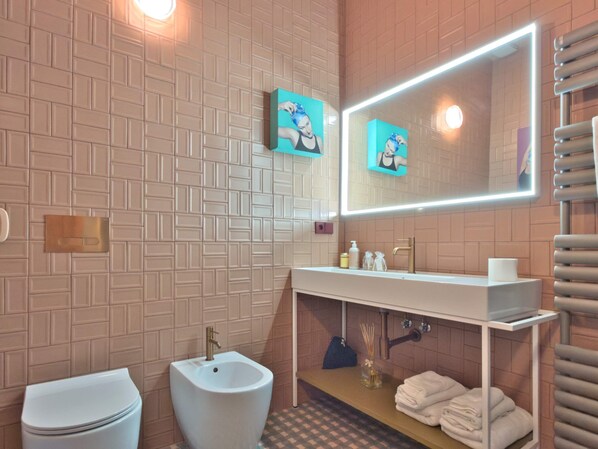 Une salle de bain moderne équipée d’un bidet, d’un lavabo avec un miroir et d’un porte-serviettes.