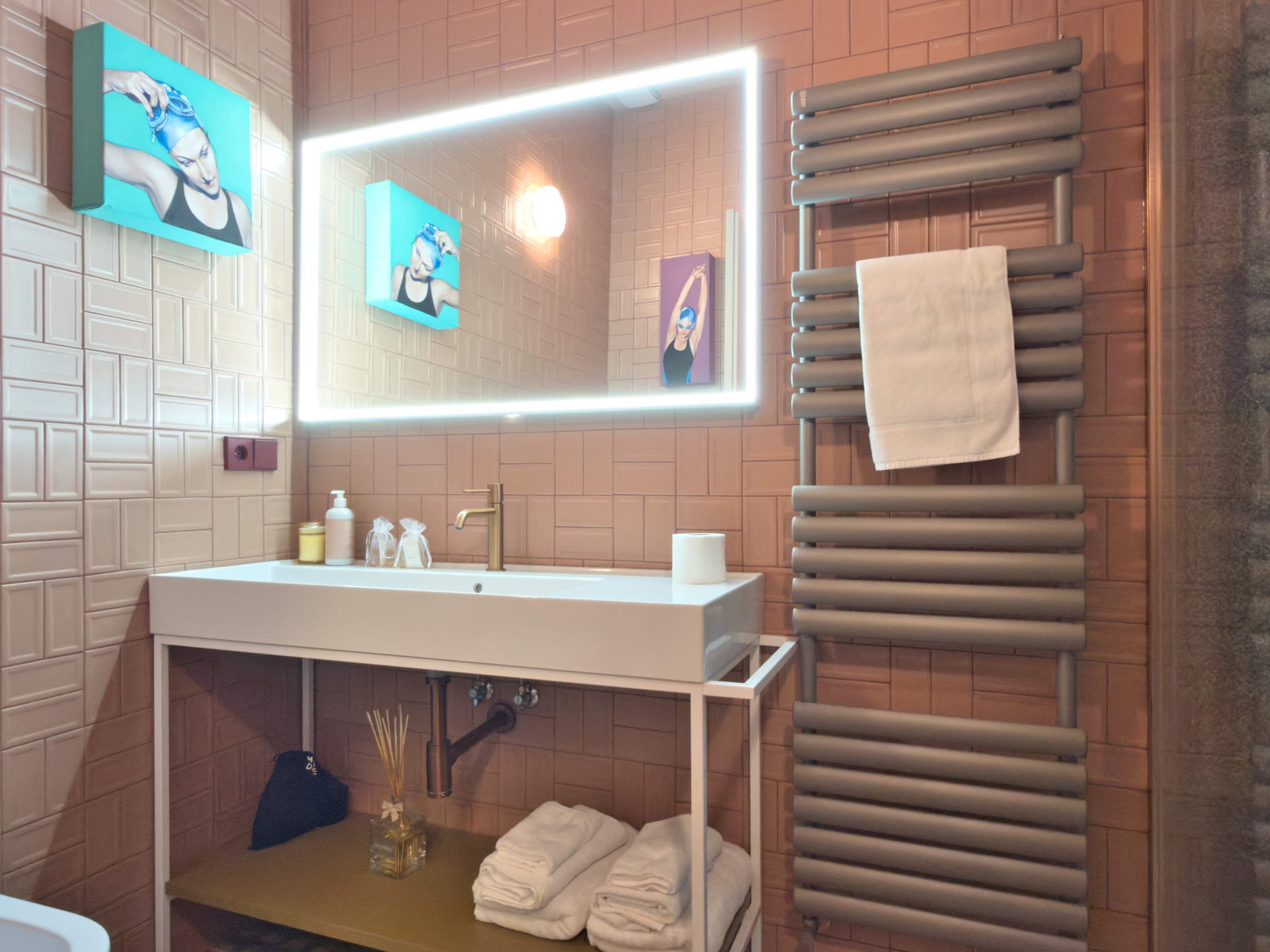 Une salle de bain moderne avec un lavabo blanc, un grand miroir et un porte-serviettes.