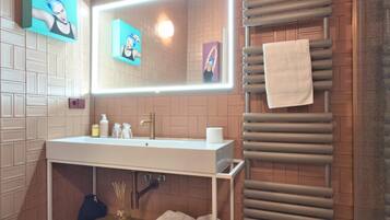 Une salle de bain moderne avec un lavabo blanc, un grand miroir et un porte-serviettes.