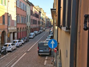 Une rue pavée bordée de voitures garées et d’immeubles aux couleurs vives.