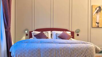 Une chambre d’hôtel avec un lit, une tête de lit, une lampe fixée au mur et un tableau.