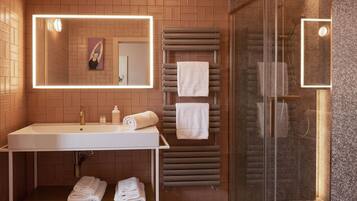 Une salle de bain moderne avec un grand miroir, un lavabo, un porte-serviettes et un espace douche.