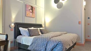 Une chambre moderne avec un lit, des luminaires fixés au mur et un tableau.