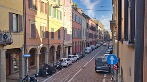 Eine Kopfsteinpflasterstraße gesäumt von bunten Gebäuden, parkenden Autos und einem klaren, blauen Himmel.