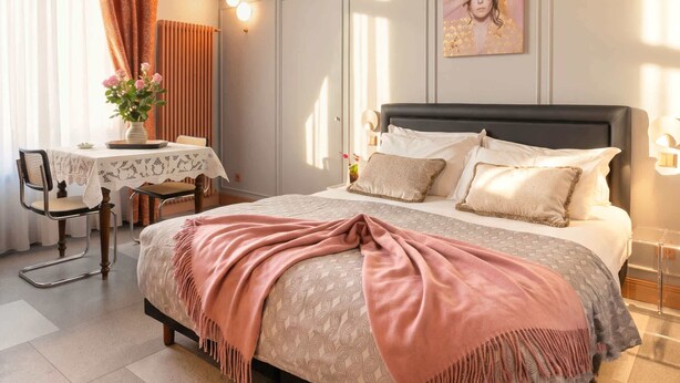 Ein Schlafzimmer mit Bett, Nachttisch, Stuhl und einem Bild an der Wand.