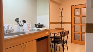 A compact kitchen with a wooden countertop, a sink, and a dining area with a table and chairs. - 30sec walk to Tsutenkaku/1 stop to Namba Sta./AH68 (Ebisu Higashi Naniwa-Ward,Osaka City)