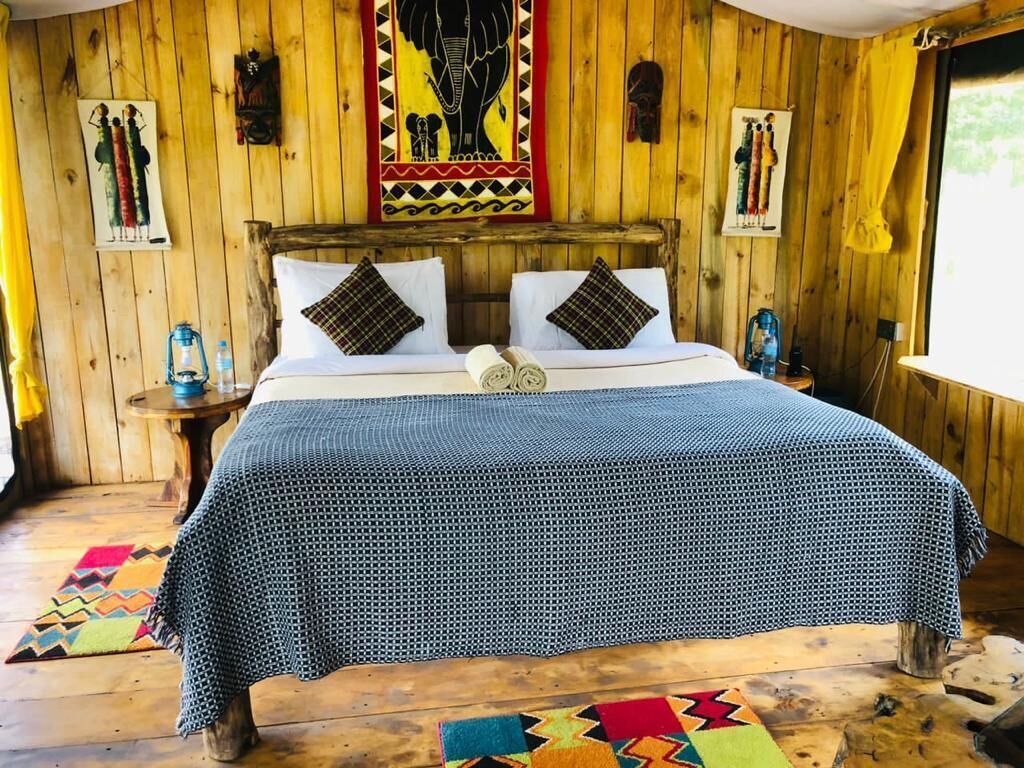 A wooden room with a bed, a nightstand, and a wall with cultural artwork.