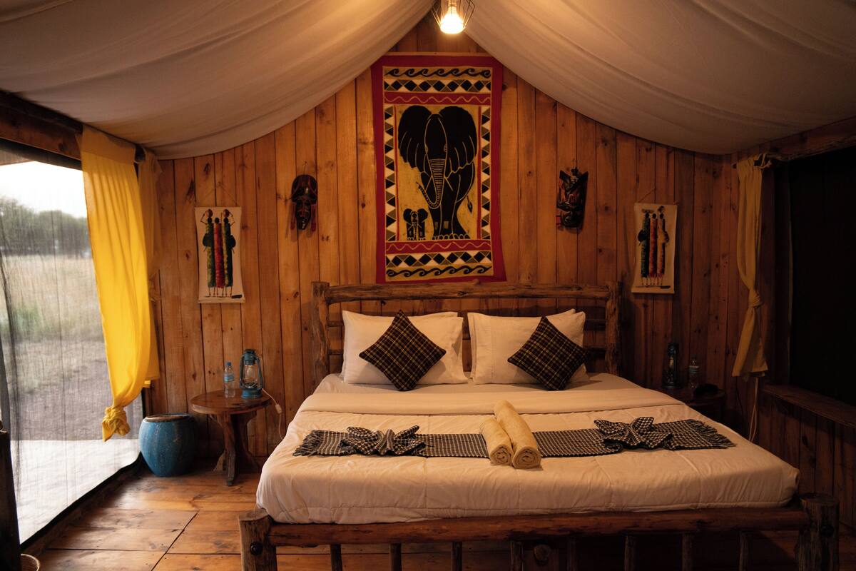 Ein Zimmer aus Holz mit einem Bett, Vorhängen und einer Wanddekoration.