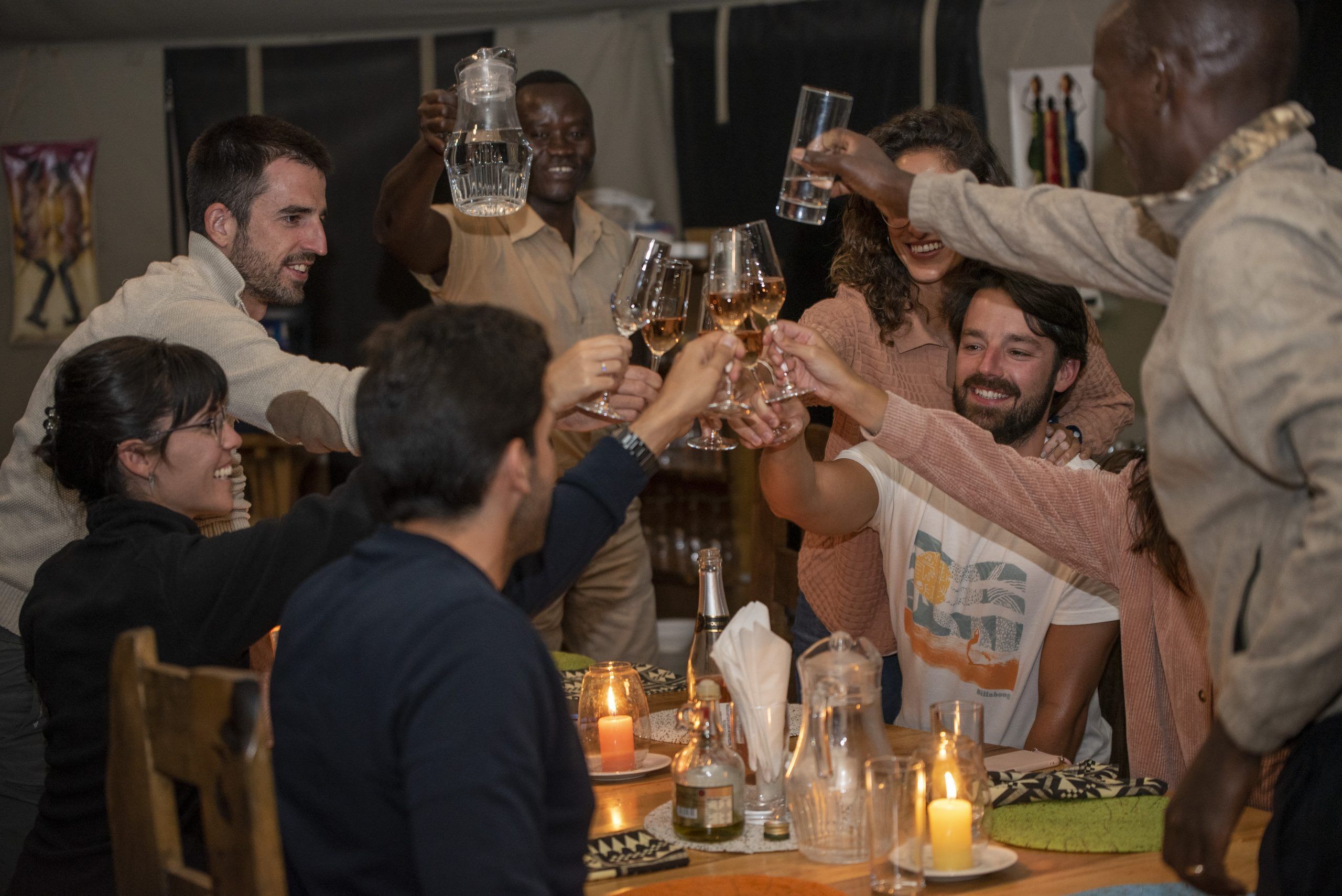 Un grupo de personas brindando con copas de vino en una mesa con velas y botellas.