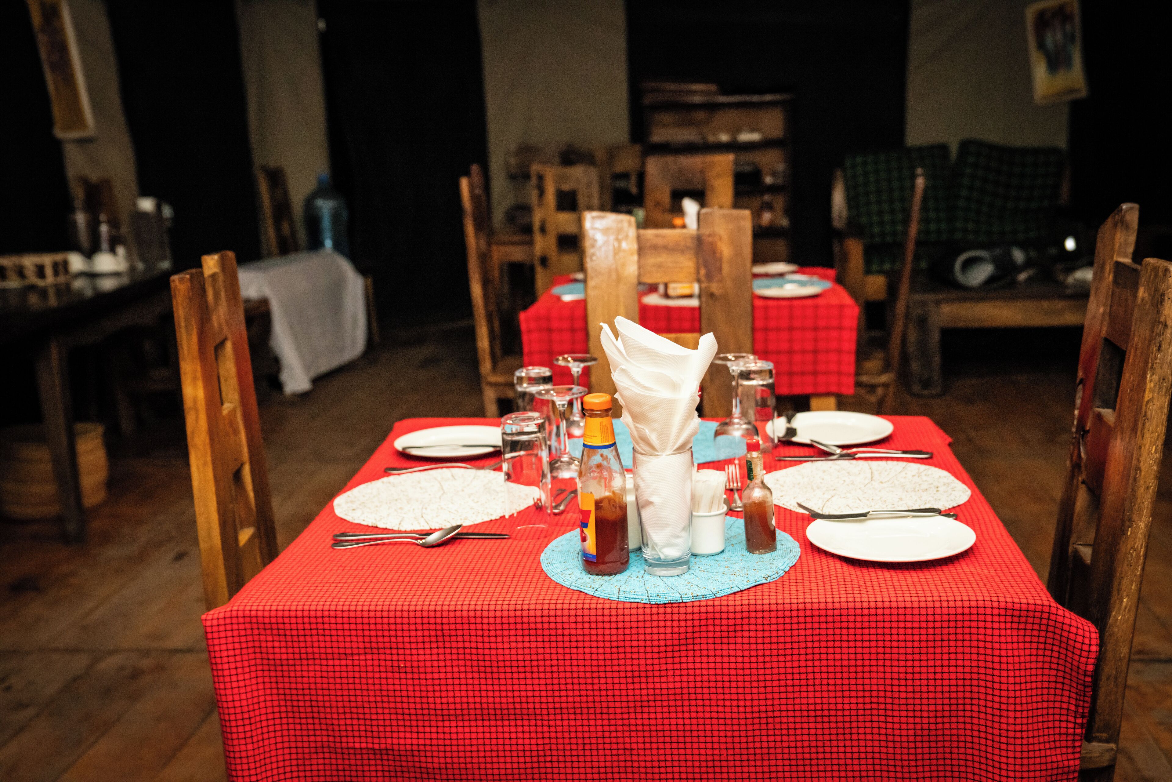 A dining table set with plates, cutlery, and condiments, surrounded by wooden chairs.