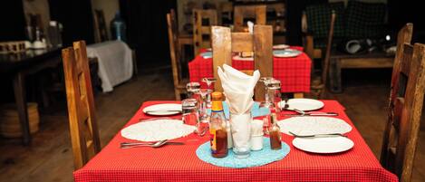 A dining table set with plates, cutlery, and condiments, surrounded by wooden chairs.