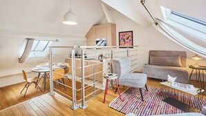 Une chambre de style loft moderne, dotée d’une mezzanine, d’une fenêtre de toit et d’un coin repas.