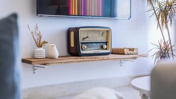 A vintage radio on a wooden shelf, a vase with dried plants, and a colorful striped artwork on the wall.