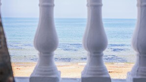 A view through a balustrade overlooking a beach with calm waters and a sandy shore. - La Vague Bleue – water feet S 04 (Marsa)
