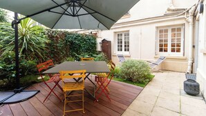 A patio with a table and chairs, a large umbrella, and a small garden area. - Chic Apartment & Terrace Eiffel Tower - Trocadero (Paris)