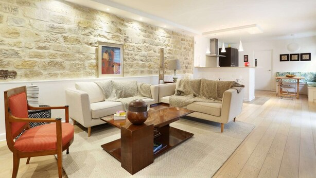 A modern living room with a stone wall, two sofas, a coffee table, and a red chair. - Chic Apartment & Terrace Eiffel Tower - Trocadero (Paris)