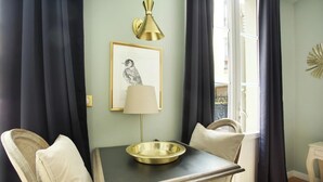 A room with a table, two chairs, a lamp, a framed picture, and a window with curtains. - Elegant Studio with AC Center of Paris - Opéra (Paris)