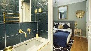 A modern bathroom with a large bathtub, a glass-enclosed shower, and a vanity with a gold faucet. - Elegant Studio with AC Center of Paris - Opéra (Paris)