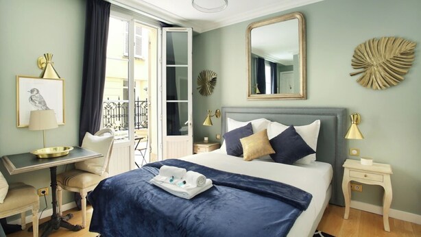 A hotel room with a bed, a desk, a chair, a small table, a mirror, and a window with curtains. - Elegant Studio with AC Center of Paris - Opéra (Paris)