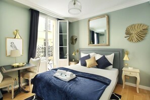 A hotel room with a bed, a desk, a chair, a small table, a mirror, and a window with curtains. - Elegant Studio with AC Center of Paris - Opéra (Paris)