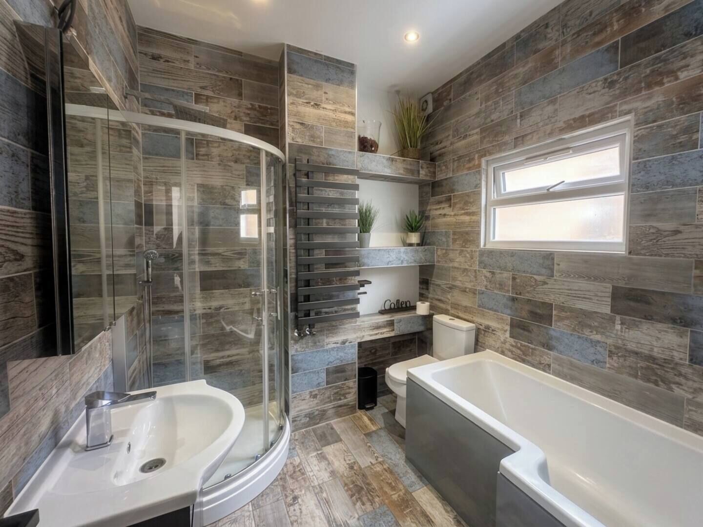 Une salle de bain moderne dotée d’une douche à parois de verre, d’une baignoire sur pied et de toilettes intégrées.